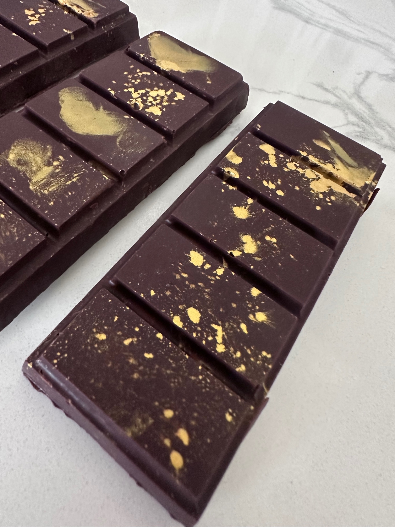 Dark chocolate Dubai bar with gold leaf and gold dust across the squares